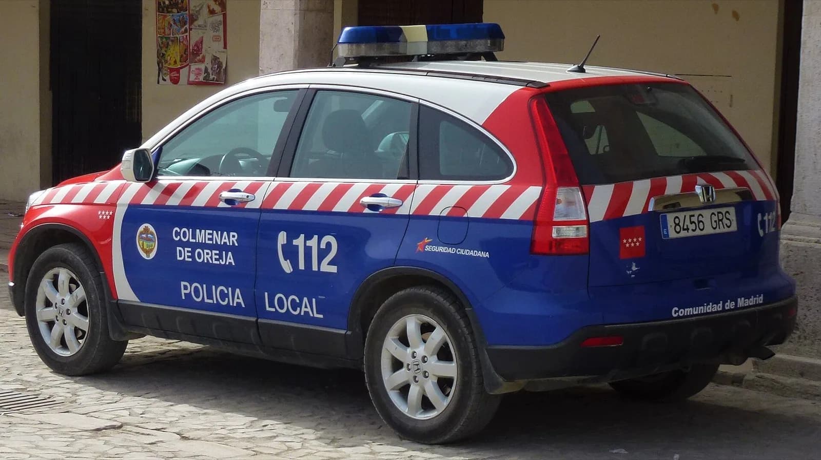 Vehículo de la Policía Local de Colmenar de Oreja aparcado en una calle empedrada